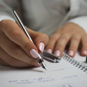 Woman in White Shirt Holding a Pen Writing on a Paper with fountain pen