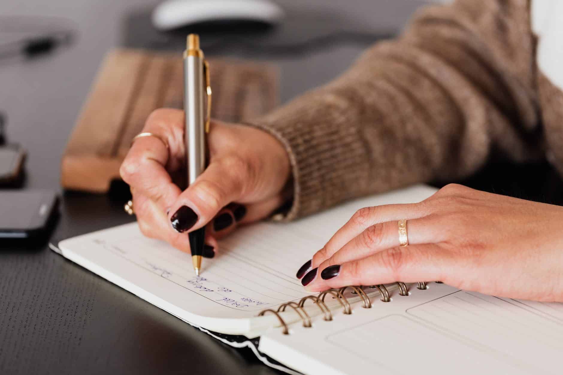 woman writing down notes in notebook