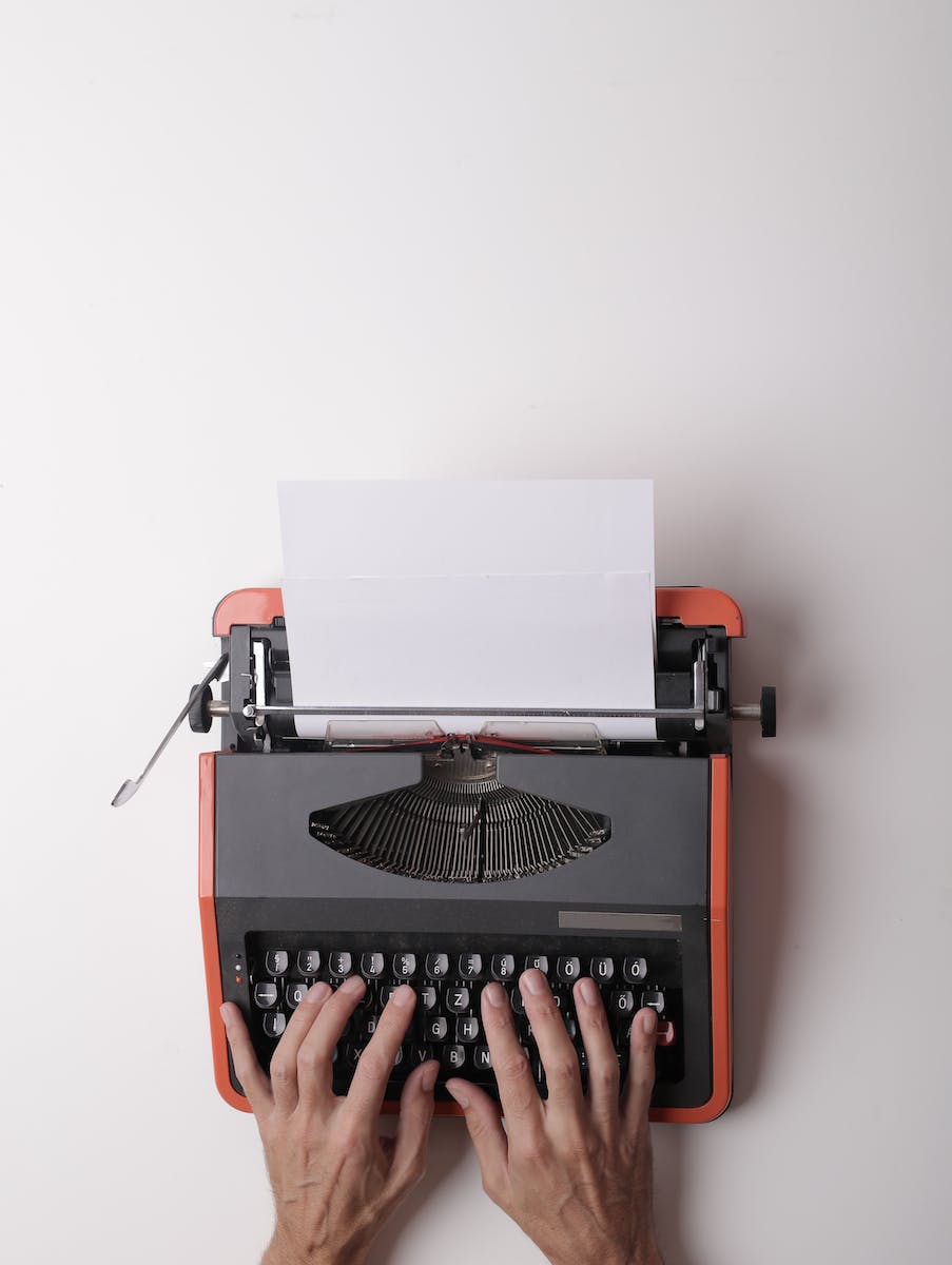 vintage black and orange typewriter with sheet of paper