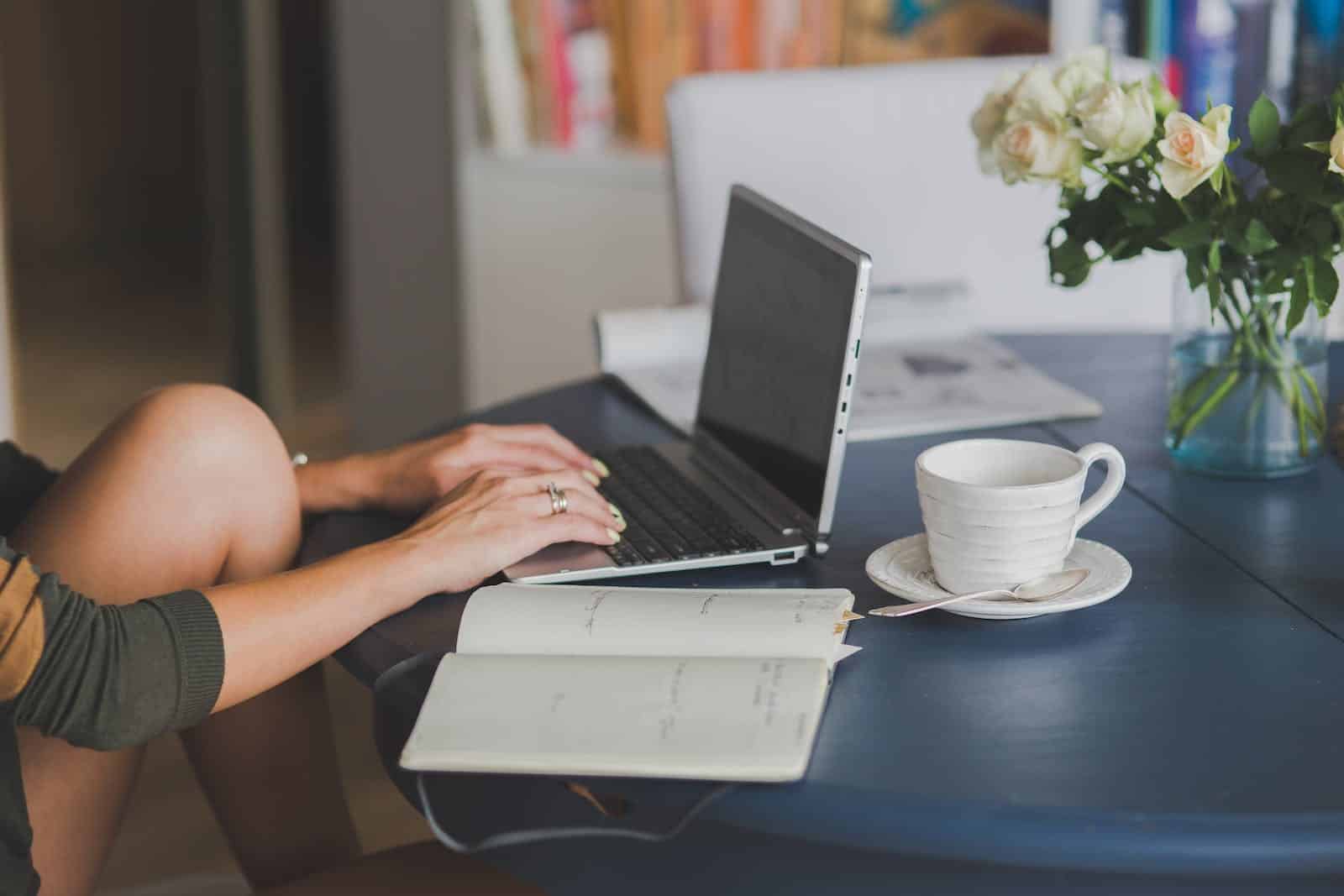 Person Using Black and Silver Laptop Computer while sitting in chair with knees folded