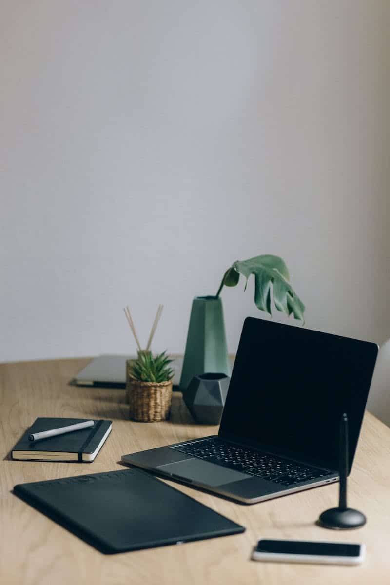 Black Laptop Computer On Wooden Table with plant and other items