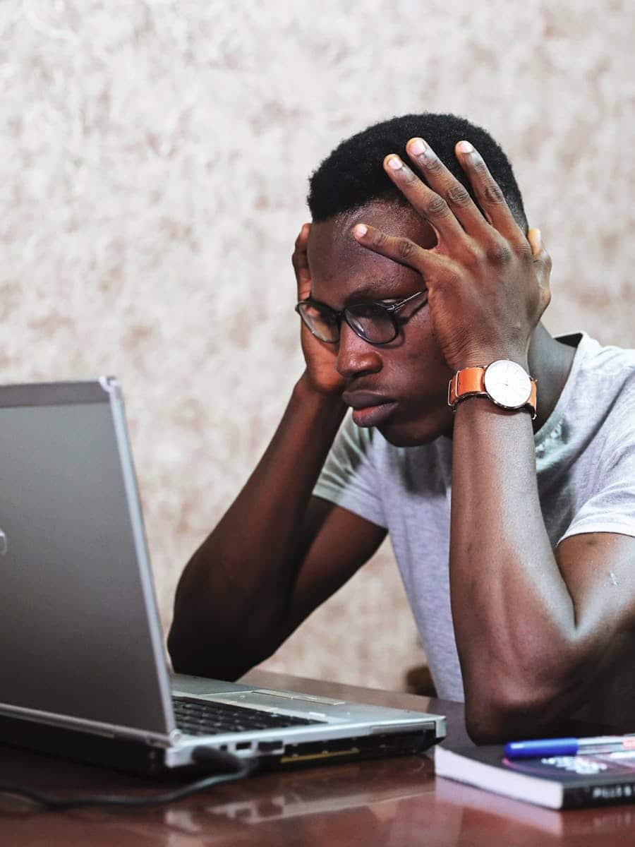 black Man looking at A Laptop with frustration