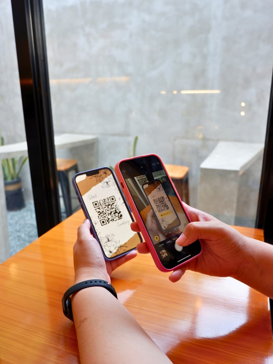 a person holding a smart phone displaying a QR code for scanning